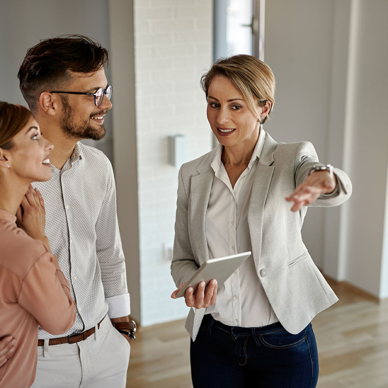 heureux-agent-immobilier-parlant-couple-tout-leur-montrant-nouvel-appartement